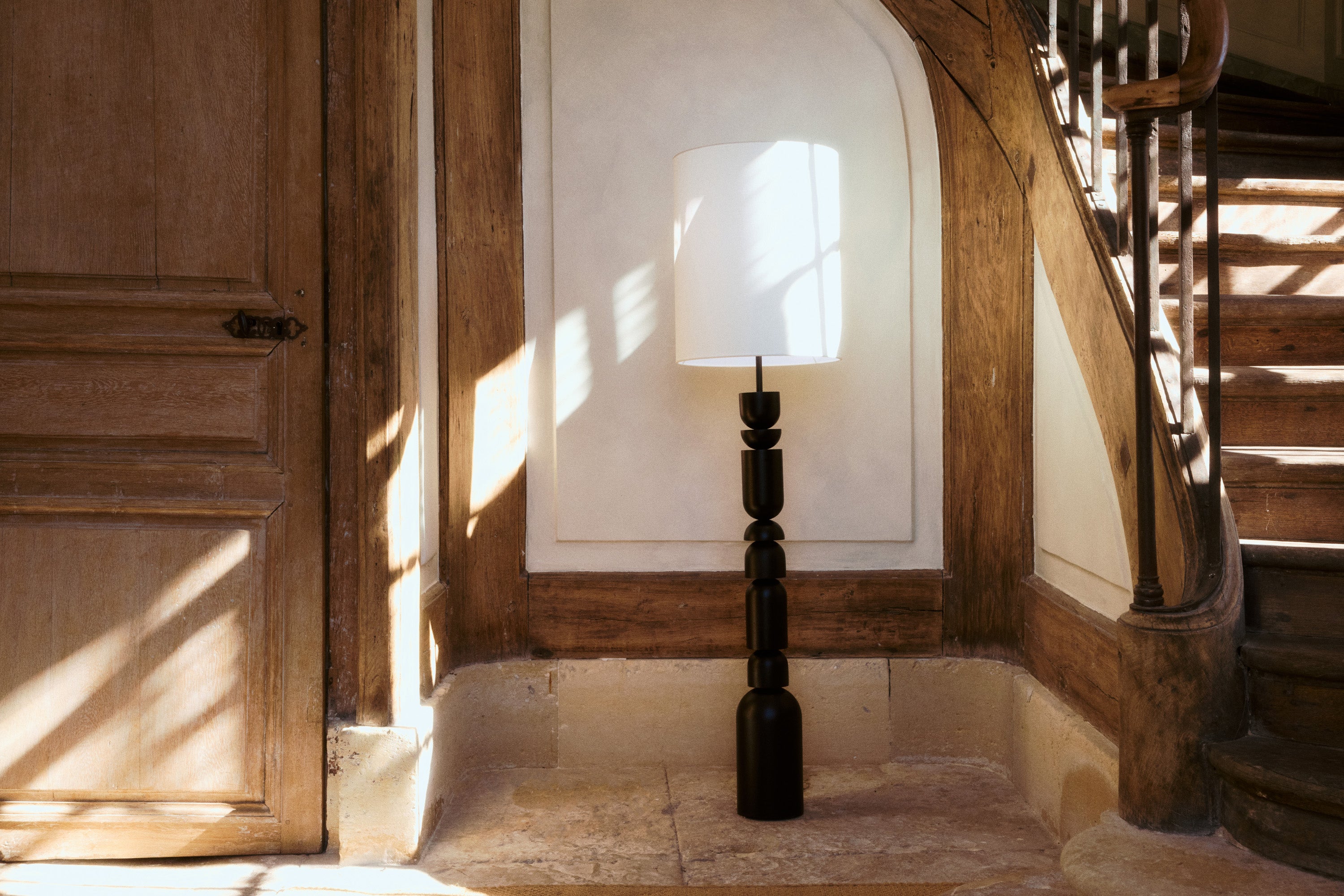 lampadaire Tinga - bois tourné noir et abat-jour lin blanc - mise en situation pied d'escalier