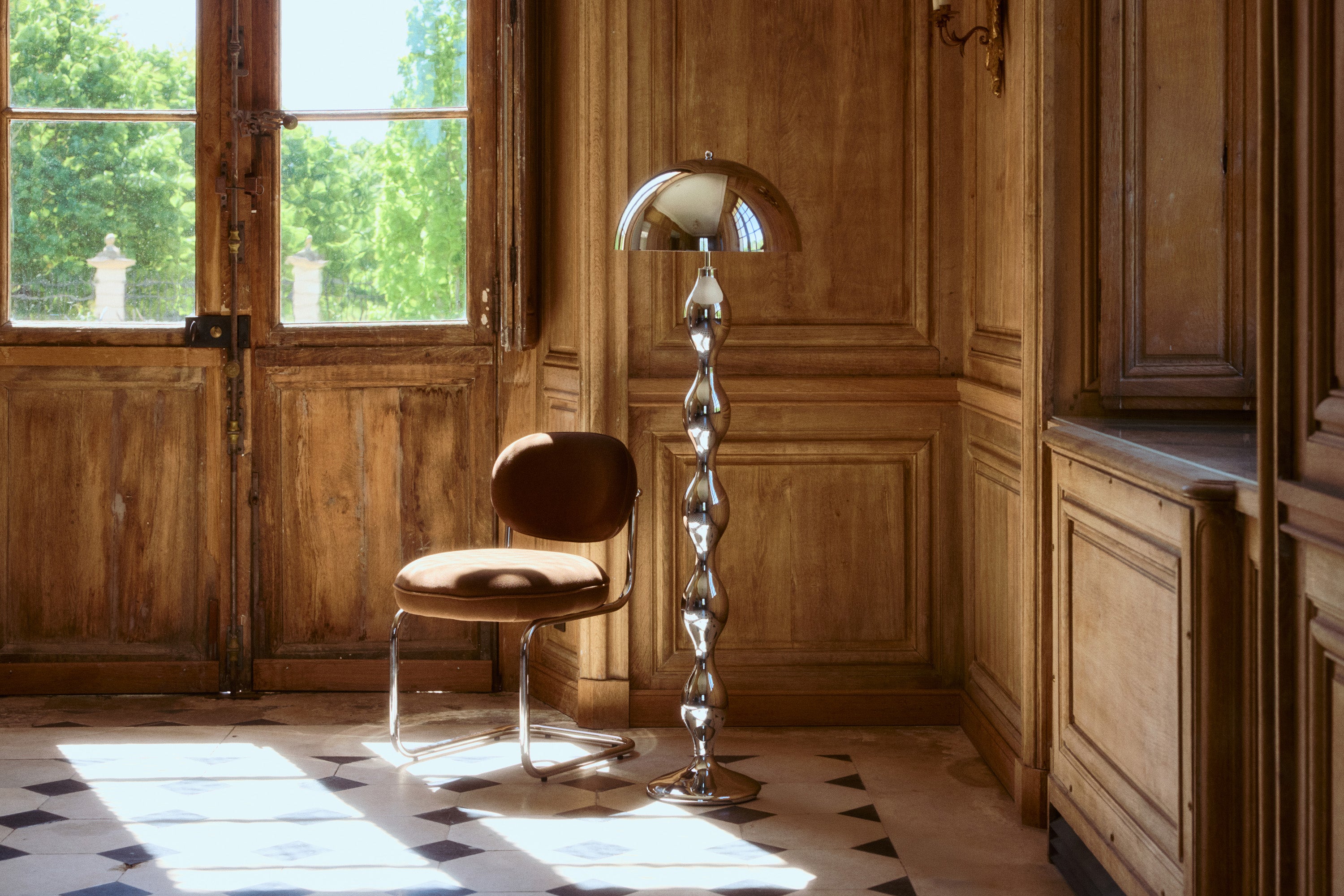 lampadaire Powers - acier chromé poli forme organique - vue d'ensemble château boiseries et carrelage damier avec chaise velours