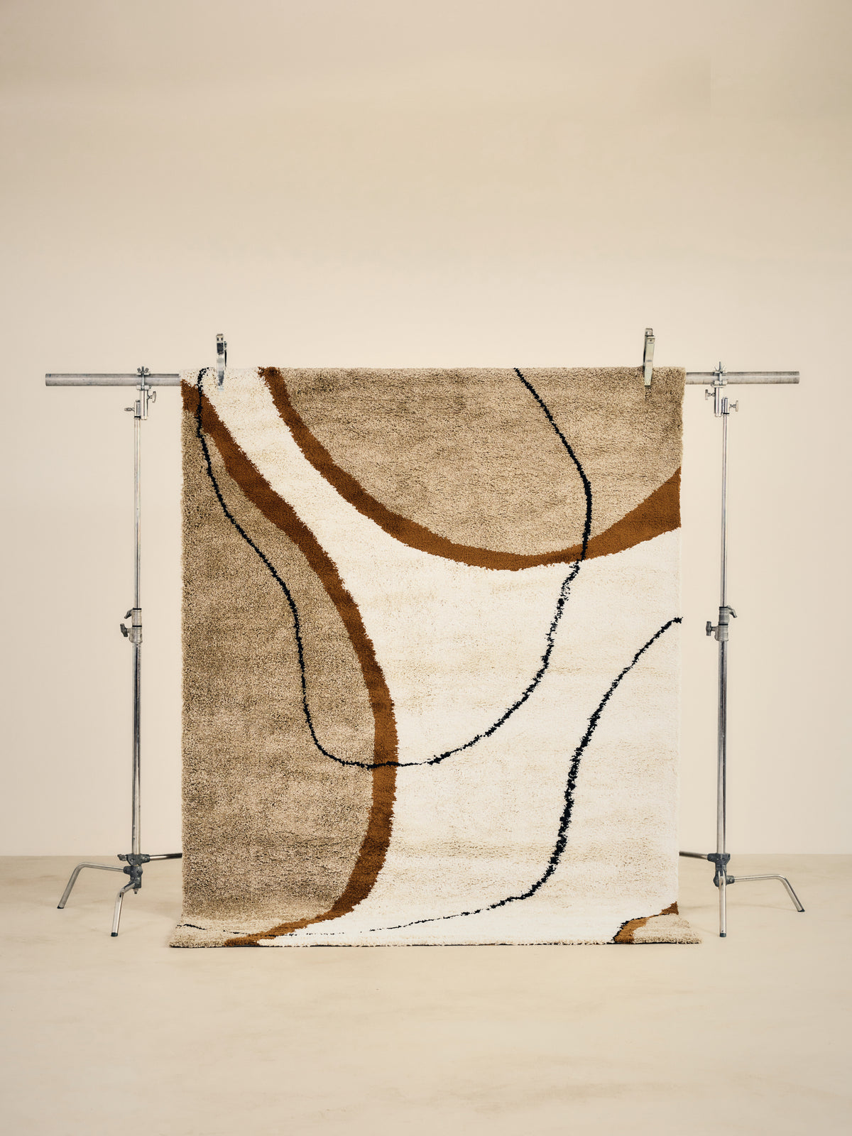 tapis de salon Solano écru à grandes courbes ocre soulignées de noir - vu portant studio