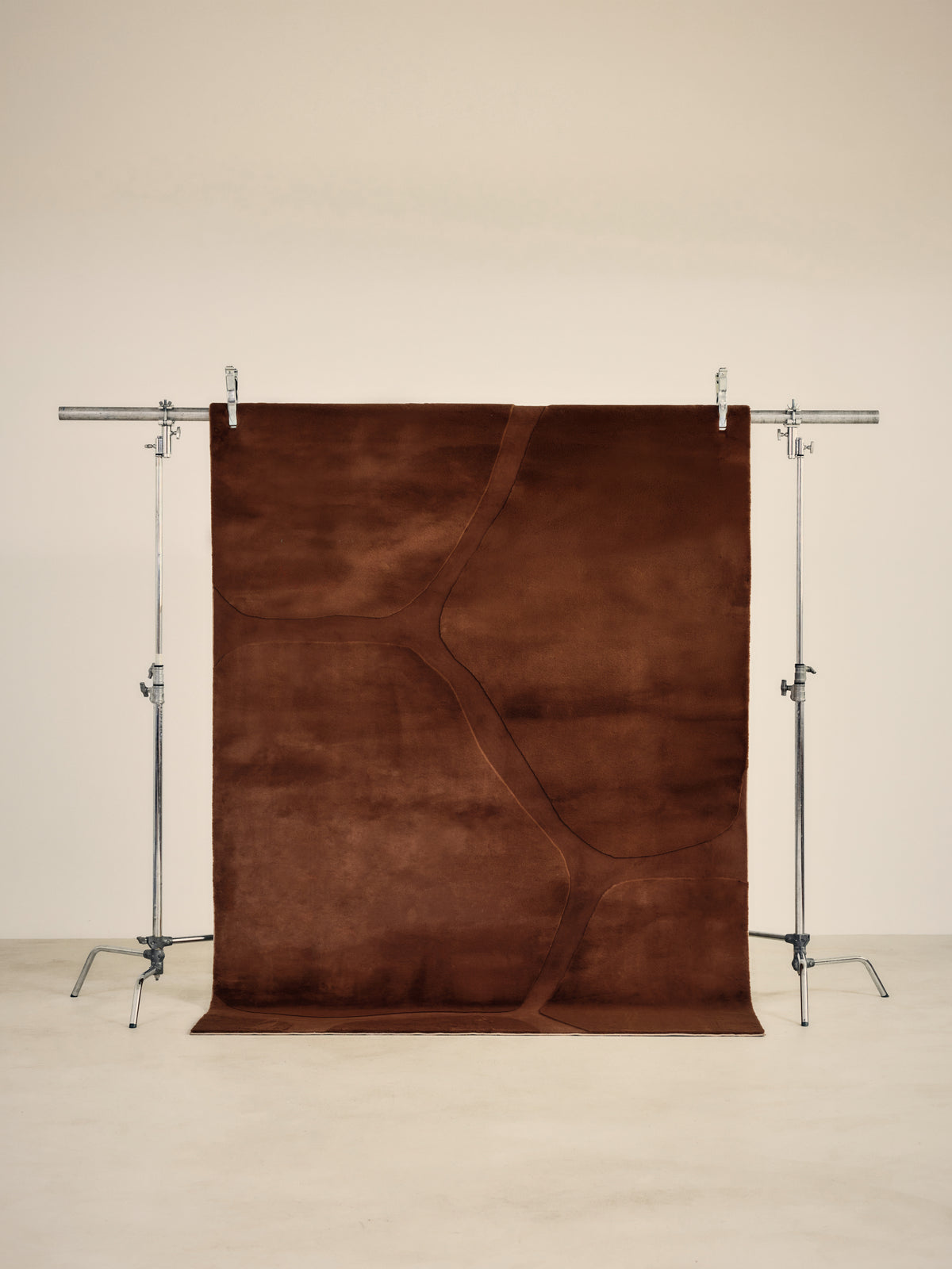 tapis de salon Shell brun rouille à cellules en relief suspendu sur un portant de studio