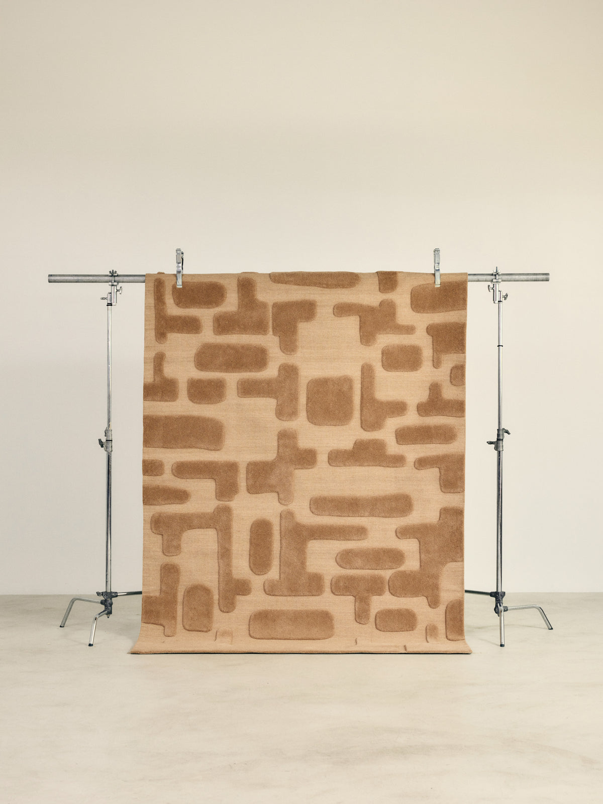 tapis de salon Maze grand format caramel à blocs en relief suspendu sur un portant