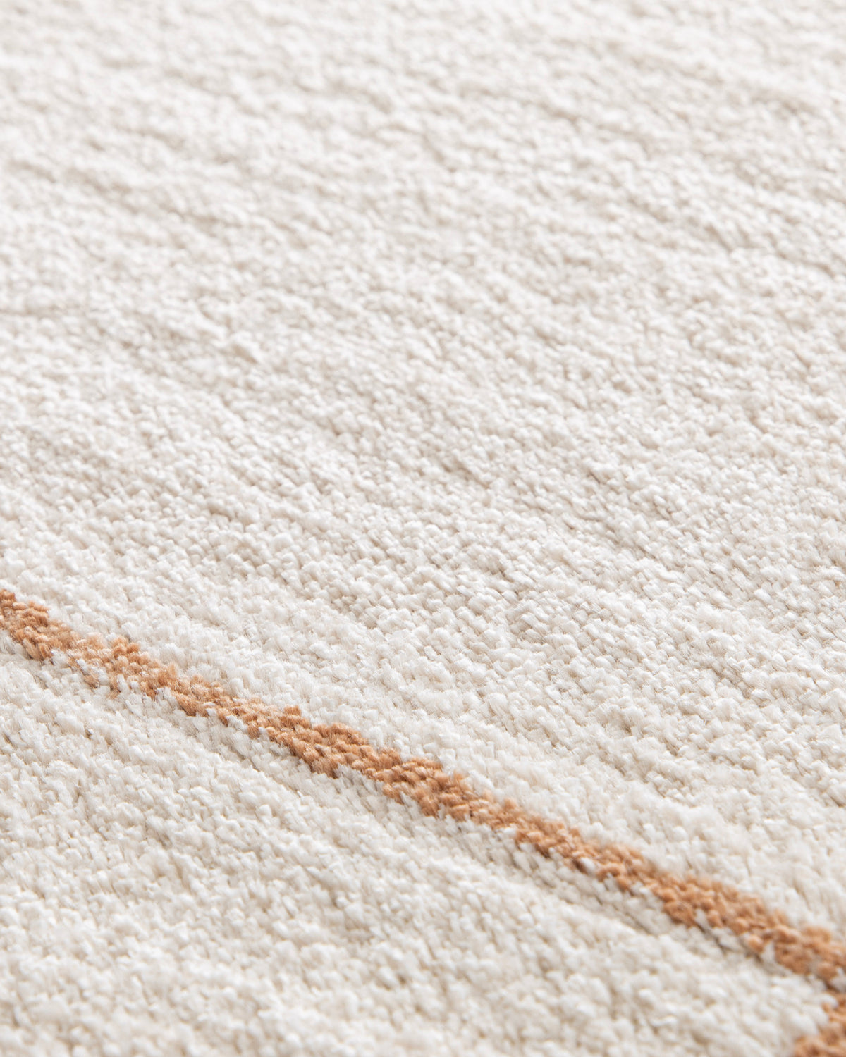 gros plan sur le velours écru et la ligne terracotta d'un tapis Crest en polypropylène