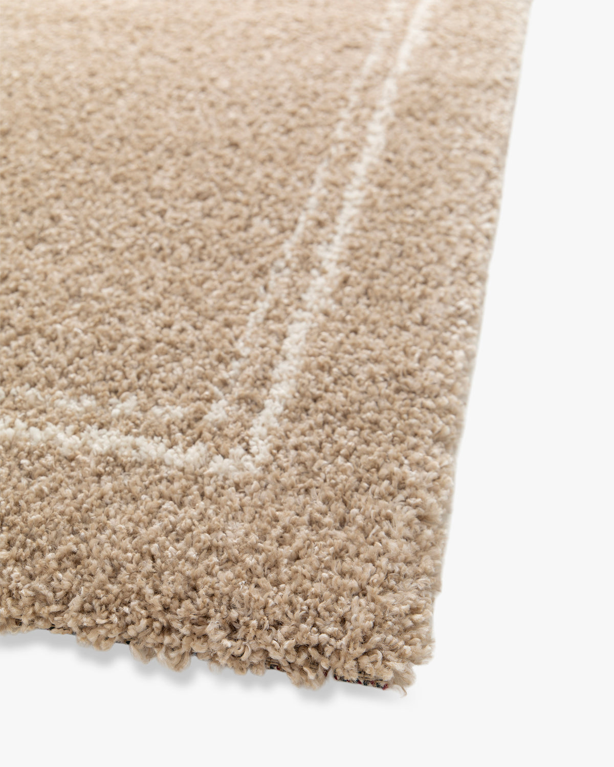 gros plan sur la double bordure écrue et le velours beige d'un tapis de salon Estero