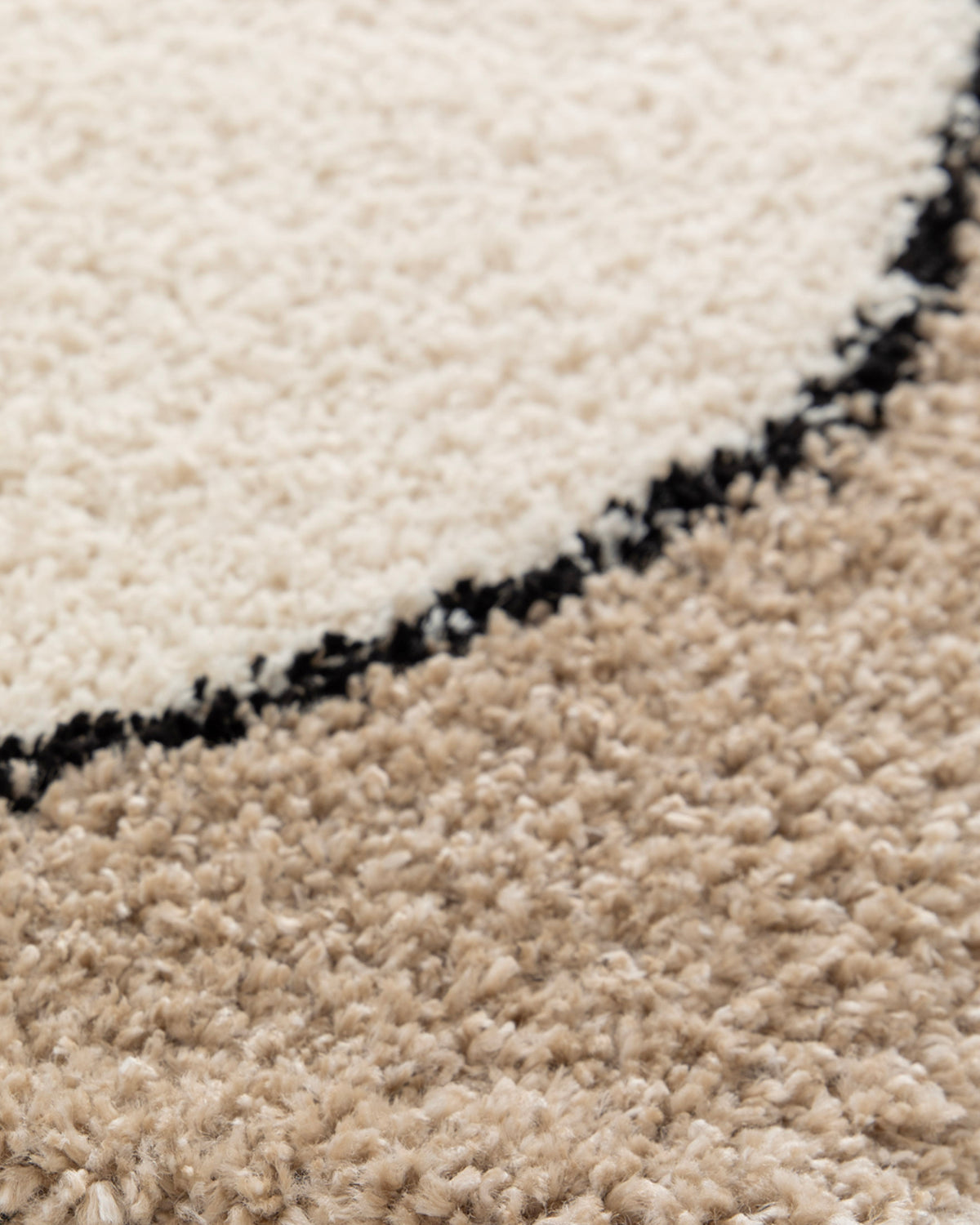 gros plan sur le tracé noir arrondi du cadre d'un tapis de salon Kento en velours écru