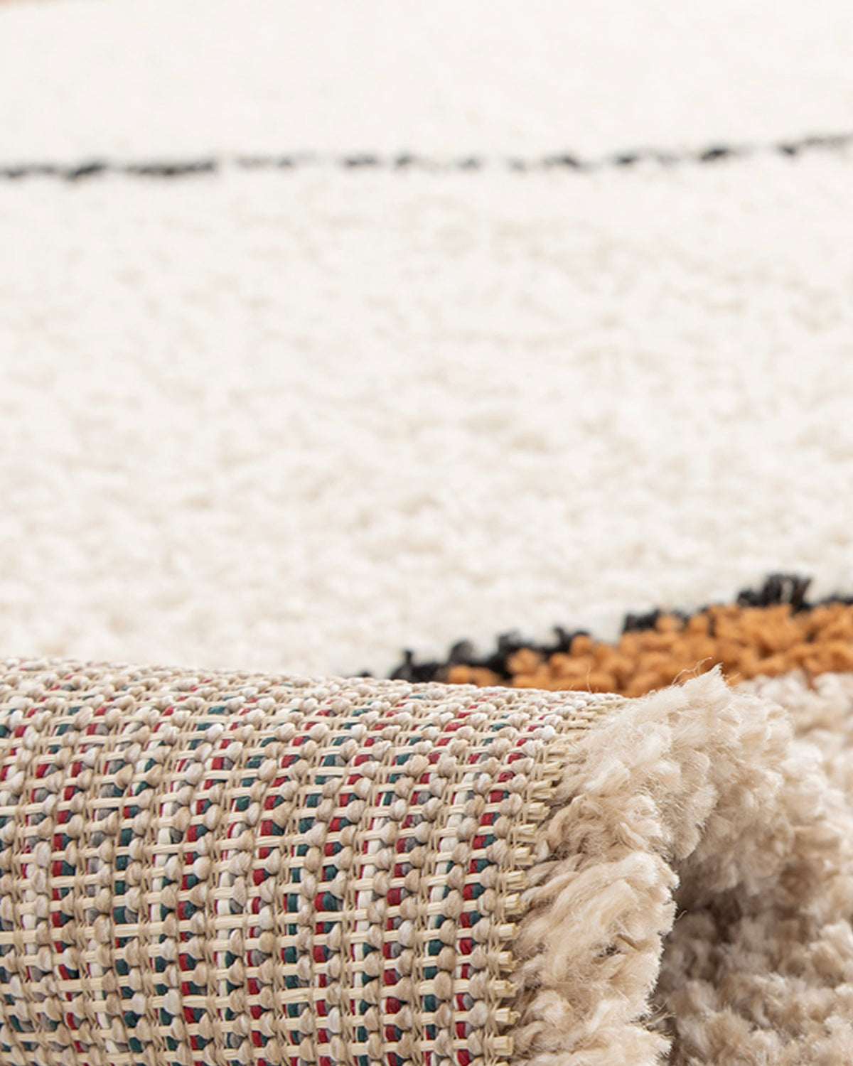 gros plan sur la courbe ocre soulignée d'un trait noir d'un tapis de salon Solano écru