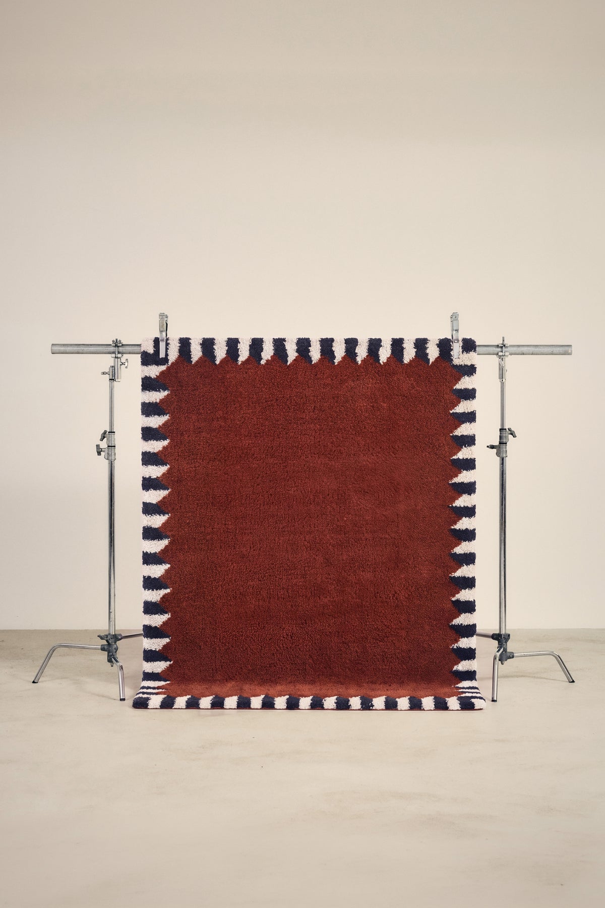 tapis ARDMORE petit format, rouge bordeaux bordé de triangles bleus et écrus, sur un portant
