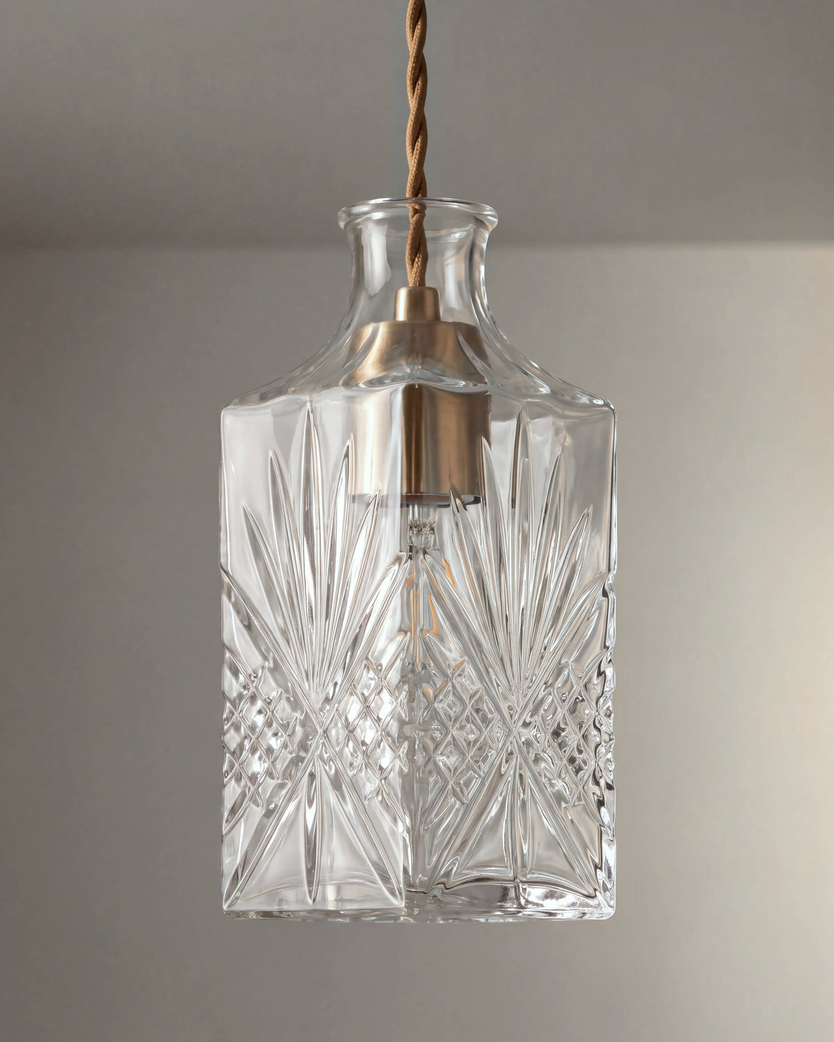 gros plan sur les motifs du verre taillé et la douille en laiton de la suspension ADLER
