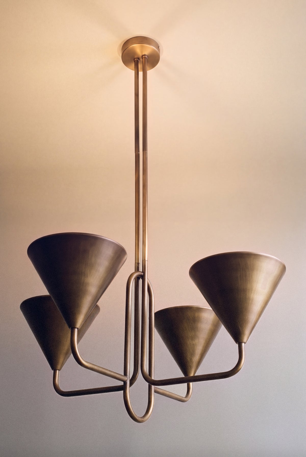 lustre ALBATRE allumé, ses quatre cônes en laiton renvoient la lumière au plafond