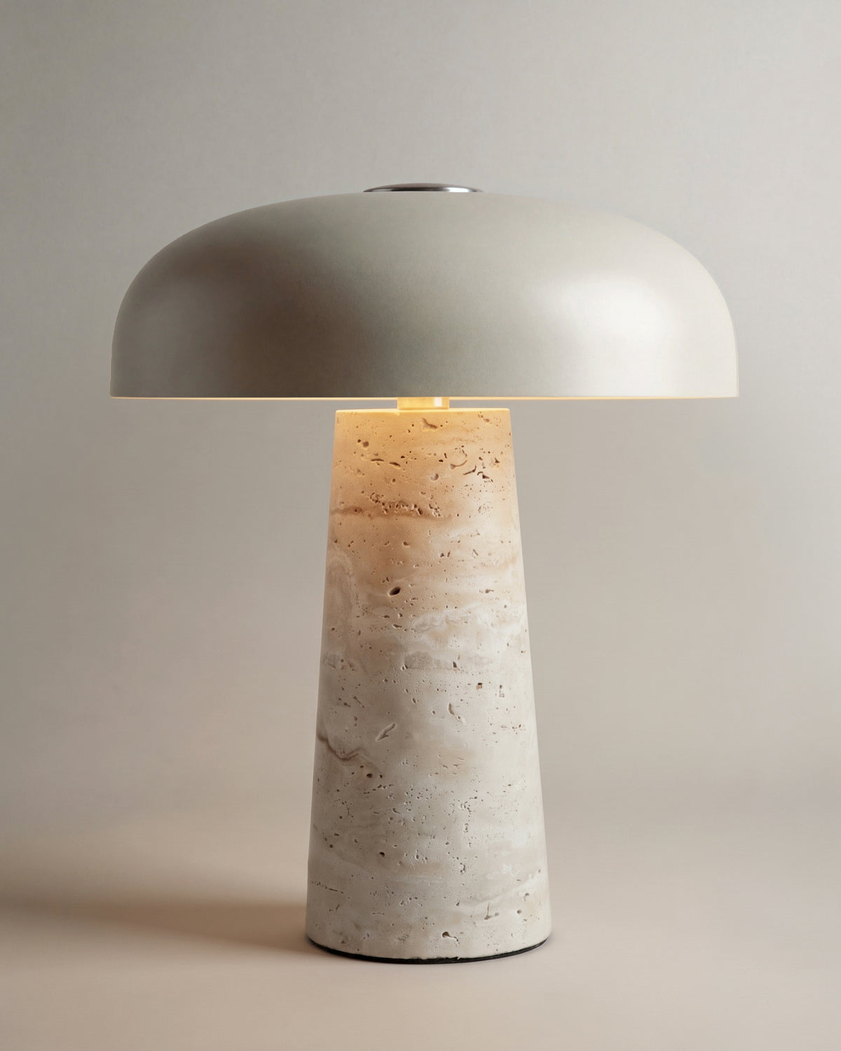 lampe de table AMANITA allumée, sa lumière descend sous le dôme et dore le travertin