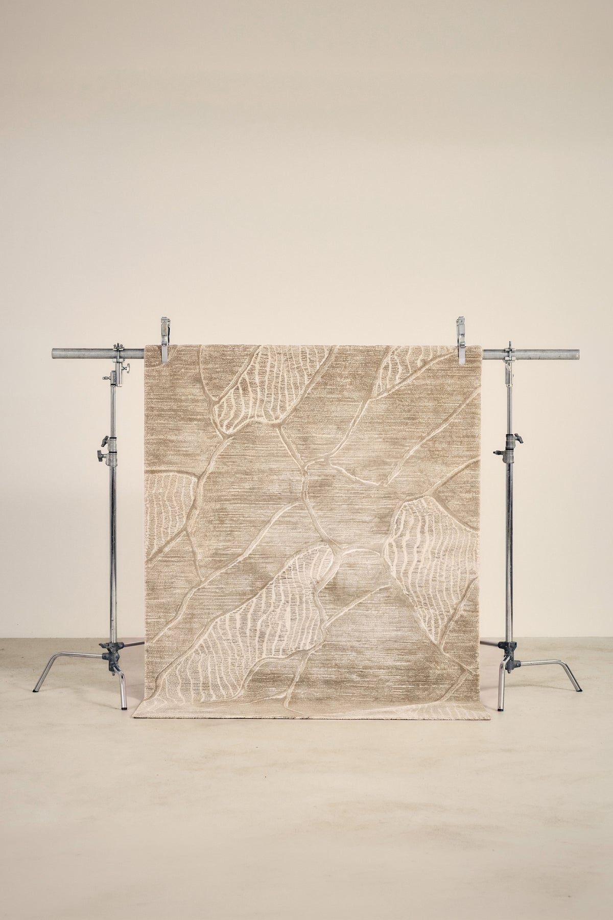 tapis FOLIO petit format, beige à nervures de feuilles écrues, sur un portant de studio