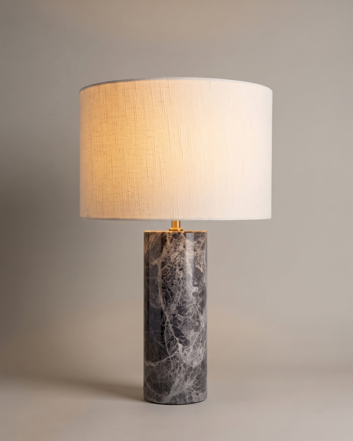 lampe de table GAIA allumée, pied cylindrique en marbre gris veiné et abat-jour en lin