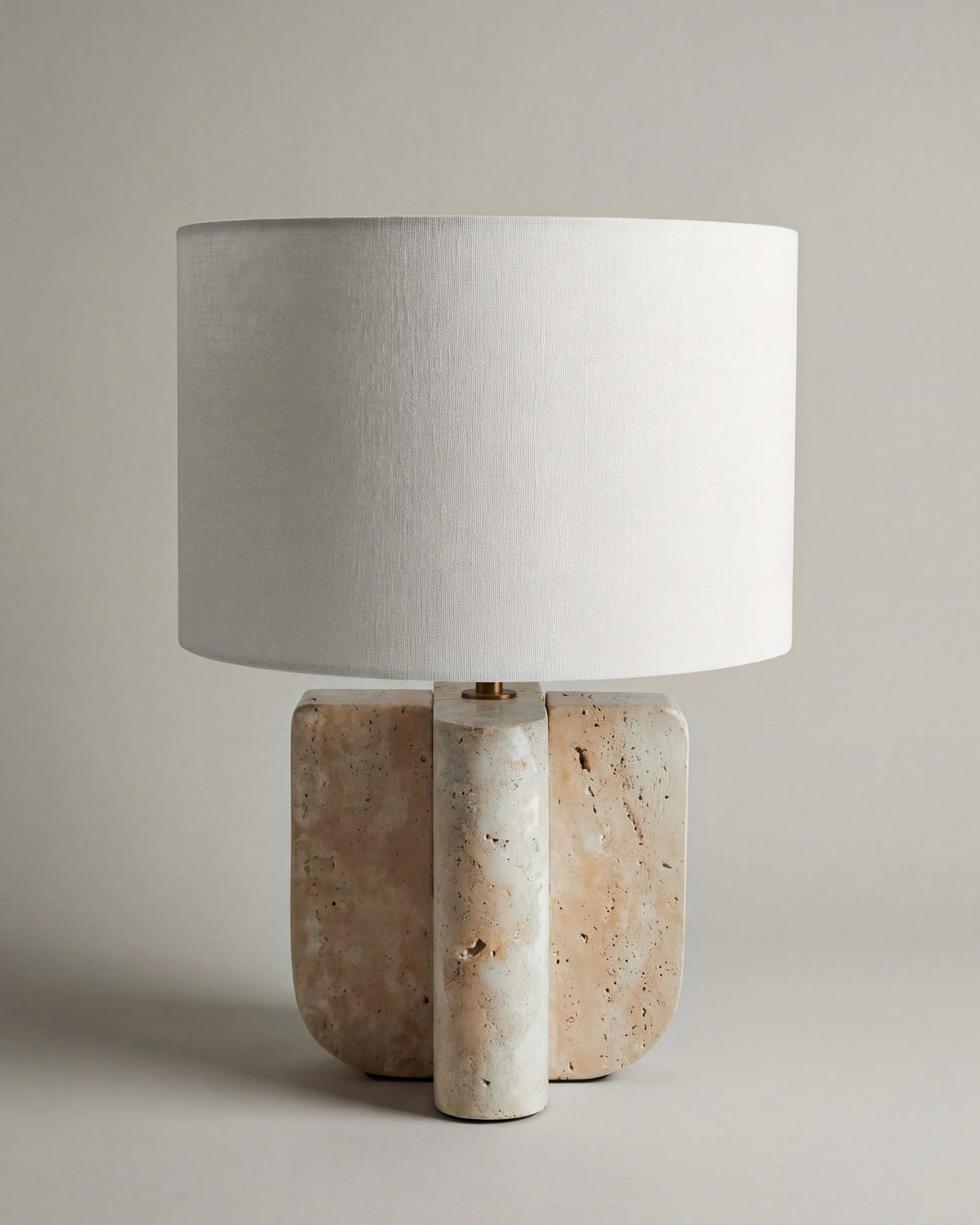 lampe de table LUMENIS éteinte, pied en travertin à trois volumes et abat-jour écru