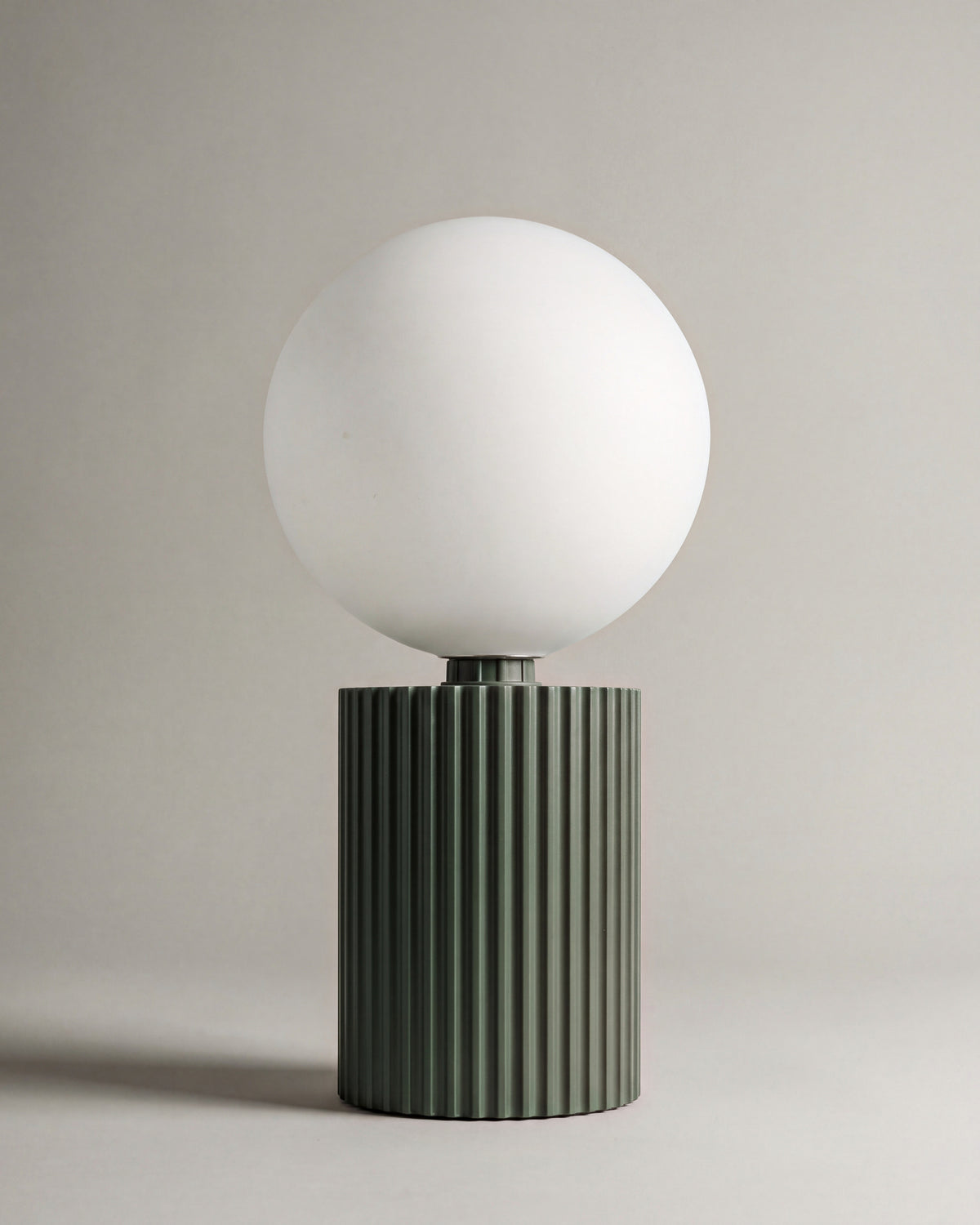 lampe de table LUNA éteinte, globe en verre opalin sur un socle cannelé vert kaki