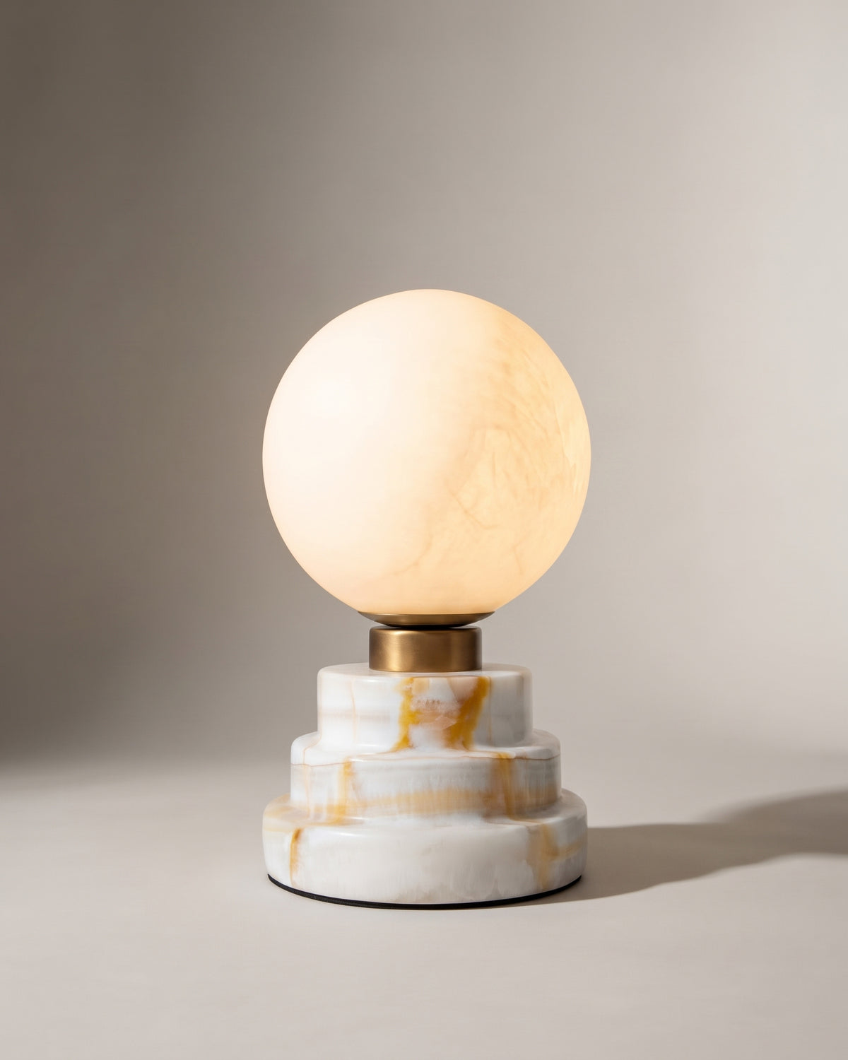 lampe de table LUNARIS allumée, globe en albâtre et base à gradins en onyx veiné d'ocre