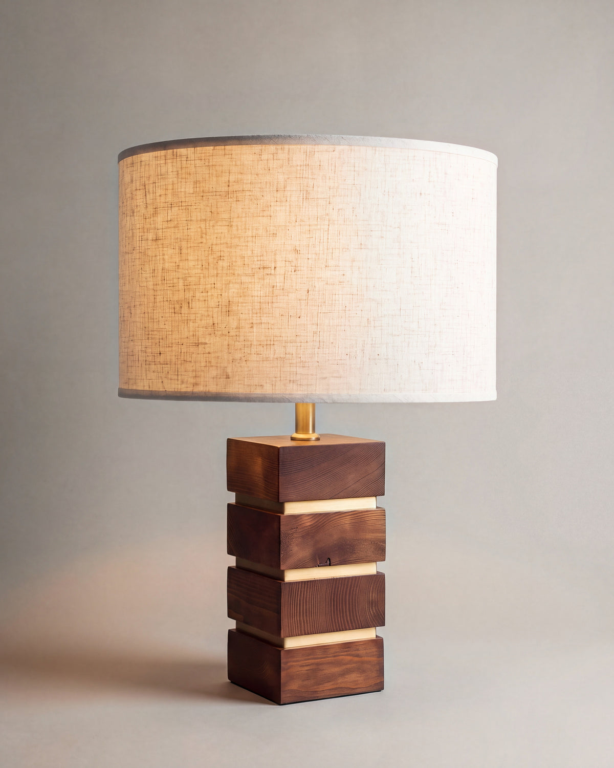 lampe de table MAKO allumée, pied en blocs de noyer empilés et abat-jour en lin écru