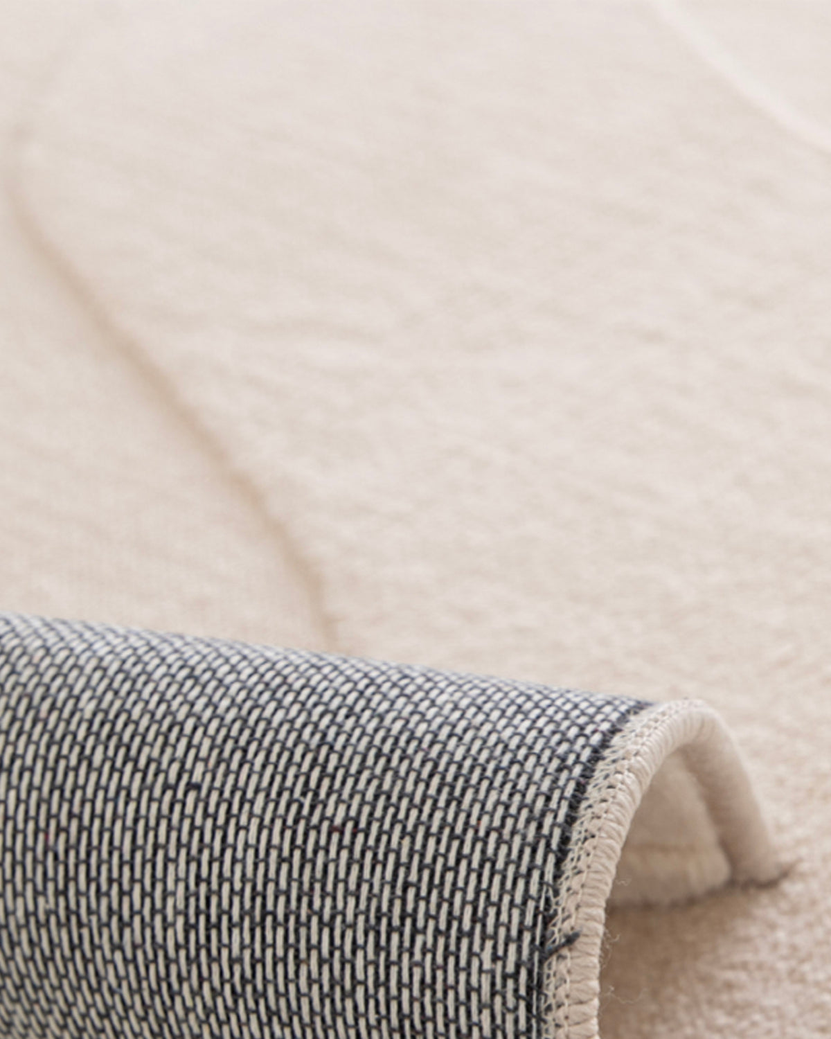 gros plan sur l'envers tissé sombre et la lisière surjetée écrue d'un tapis de salon Ikat