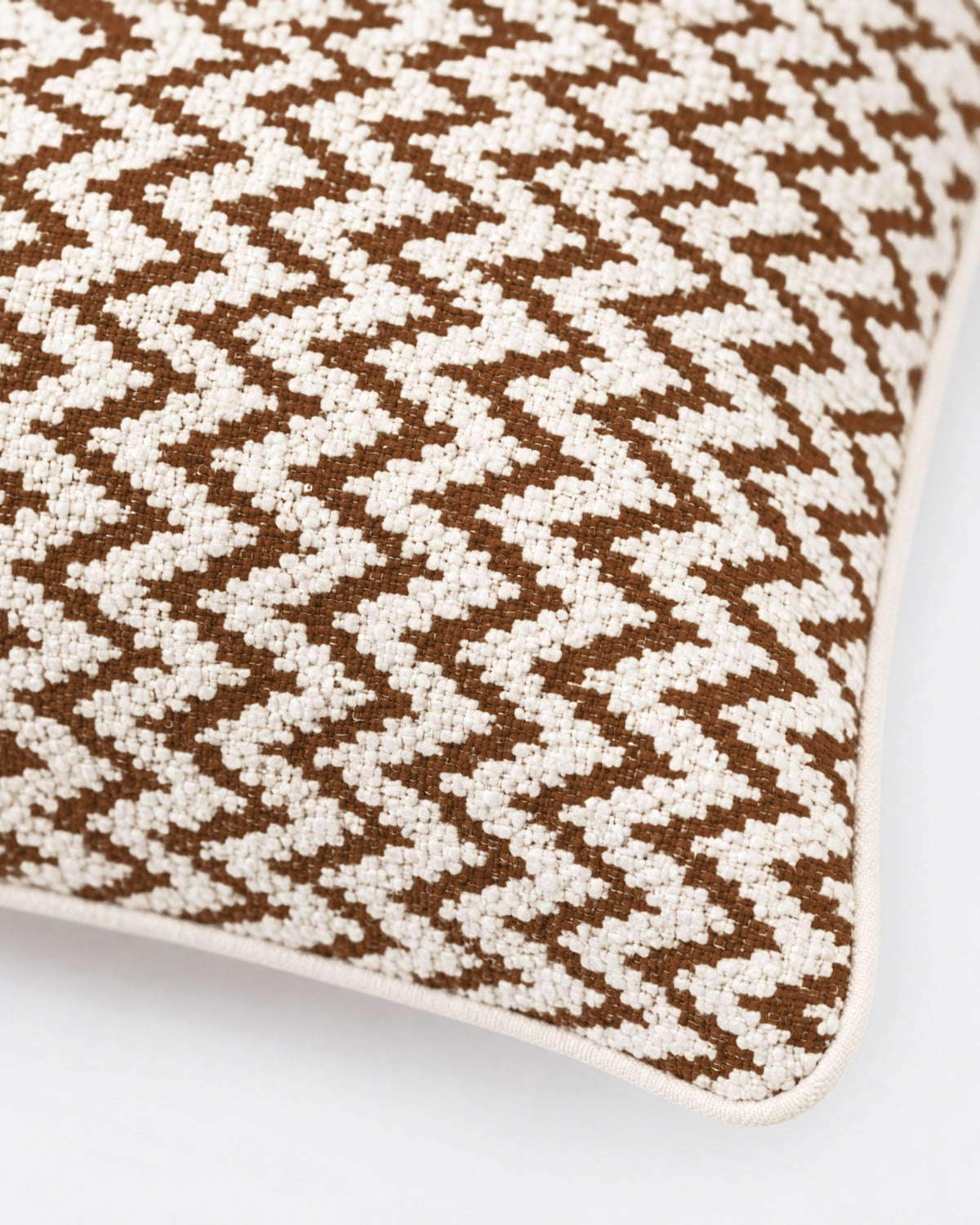 gros plan sur le tissage bouclé et les chevrons marron du coussin LODGE écru à passepoil