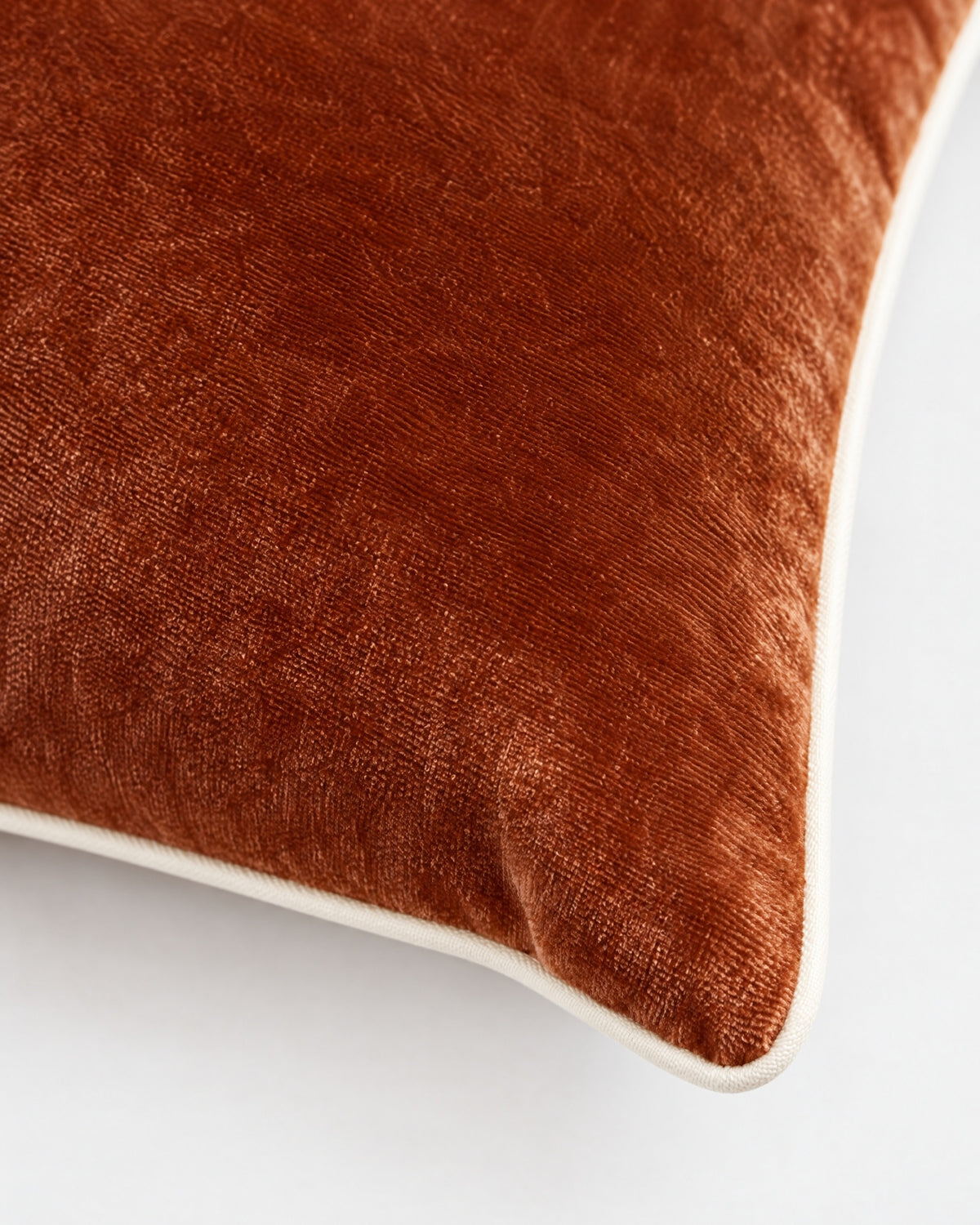 gros plan sur le passepoil écru et la texture du velours cognac du coussin LODGE