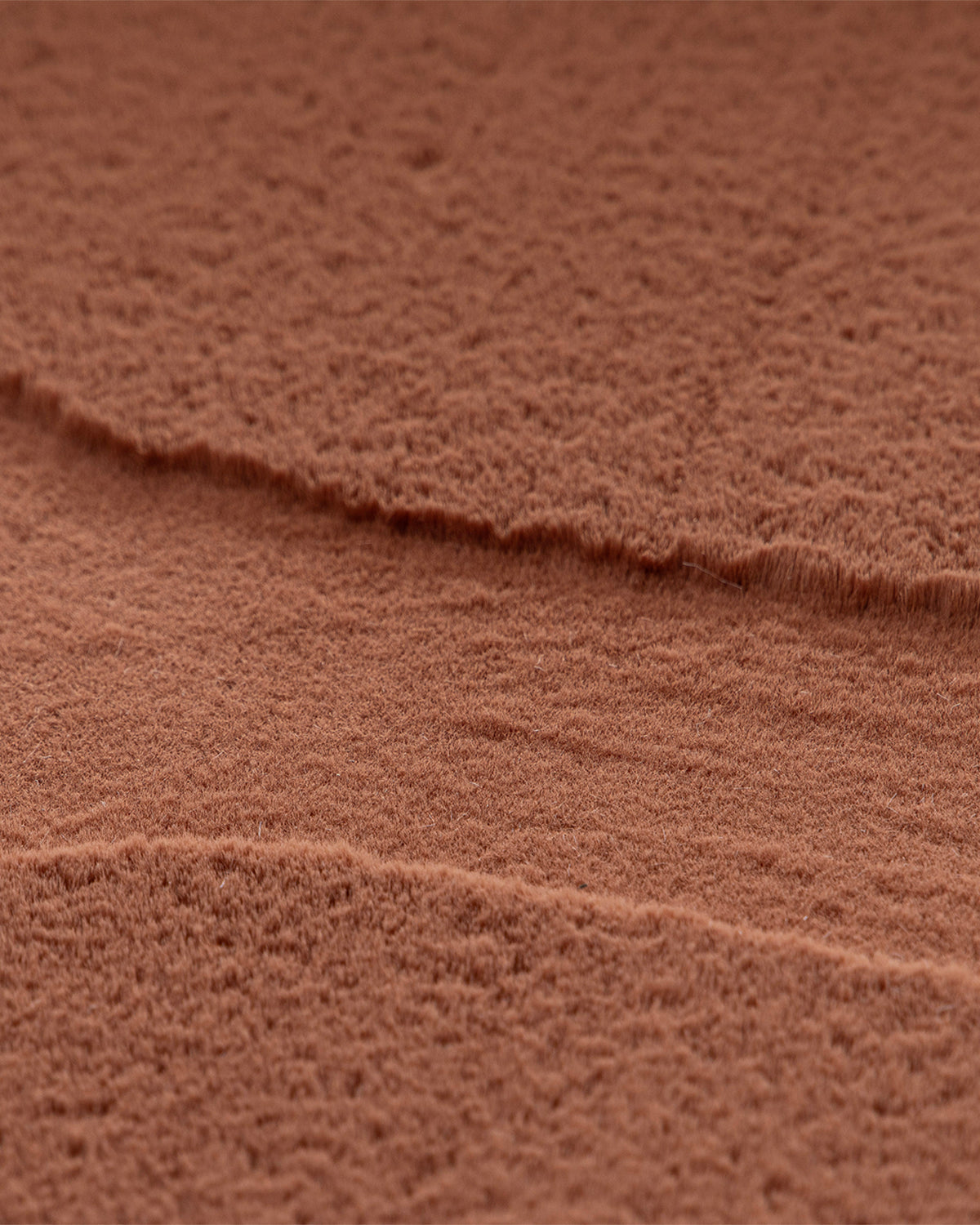 gros plan sur le velours brun terracotta du tapis SHELL et le creux entre deux cellules