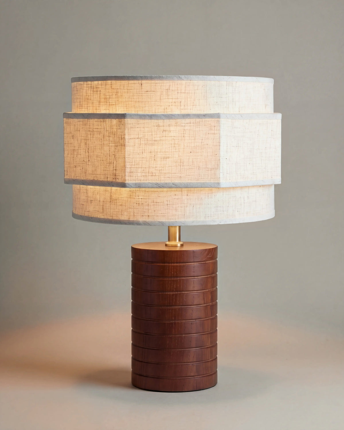 lampe de table SIA allumée, pied cylindrique en noyer rainuré et abat-jour en lin écru